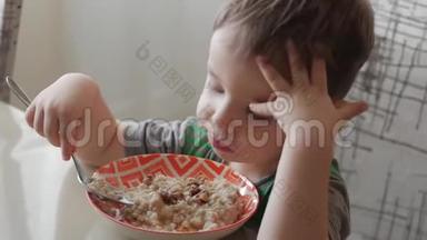 可爱的小<strong>宝宝</strong>一个人用勺子从盘子里吃粥，健康<strong>饮食</strong>的概念。